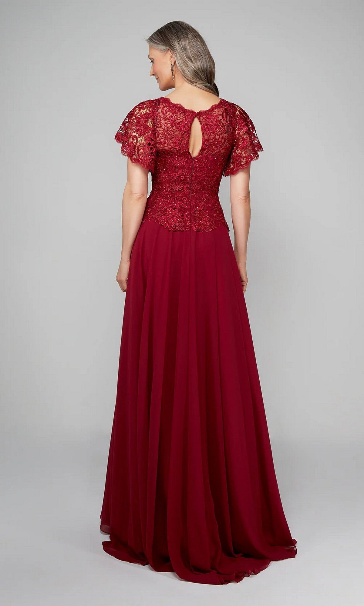 A woman faces away, wearing the Alyce 27469—a floor-length burgundy chiffon A-line dress with a lace bodice, short sleeves, and a keyhole back—against a plain background.